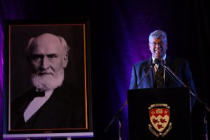 Under the watchful eye of Macdonald College founder, McGill Associate Vice Principal and Dean of the Faculty of Agricultural and Environmental Sciences Chandra Madramooto addresses the audience at the annuak Founder's Day ceremoy. / Photo: Owen Egan.