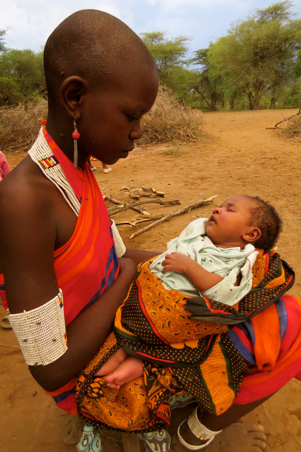 A young Maasai woman holds her newborn baby sister outside a "boma" on the Olkiramatian Group Ranch - located at the base of Kenya's Rift Valley. / Photo: Sioban Lazenby