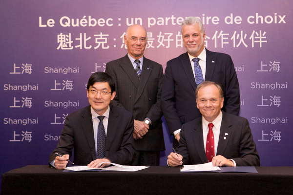 McGill's Vice-Dean of Life Sciences, Philippe Gros (seated right), and signs the agreement with Wen Chen, Dean, Fudan School of Public Health as Occupational Health Professor Paul Héroux (standing, left) and Quebec Premier Phillippe Couillard look on. / Photo: Patrick Alleyn