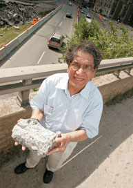 Saeed Mirza tient un morceau de ciment qui s'est effrité; il est photographié sur l'échangeur des avenues des Pins et du Parc, au centre-ville de Montréal, actuellement en rénovation.