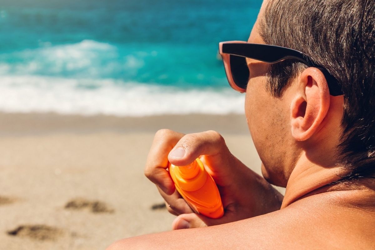 A man applies sunscreen while at the beach