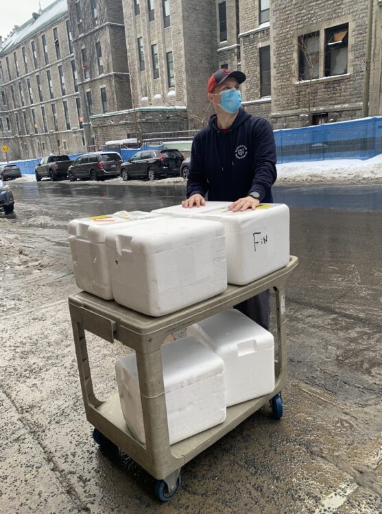 A lab member at The Neuro next to Styrofoam coolers to be picked up by Mission Bon Accueil