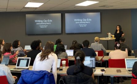 Roxanne Khamsi standing in front of a classroom next to a screen that says 'Writing Op-Eds'