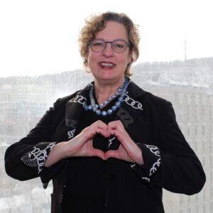 Carola Weil, Dean of the School of Continuing Studies, forming the #InspireInclusion heart pose with her hands.
