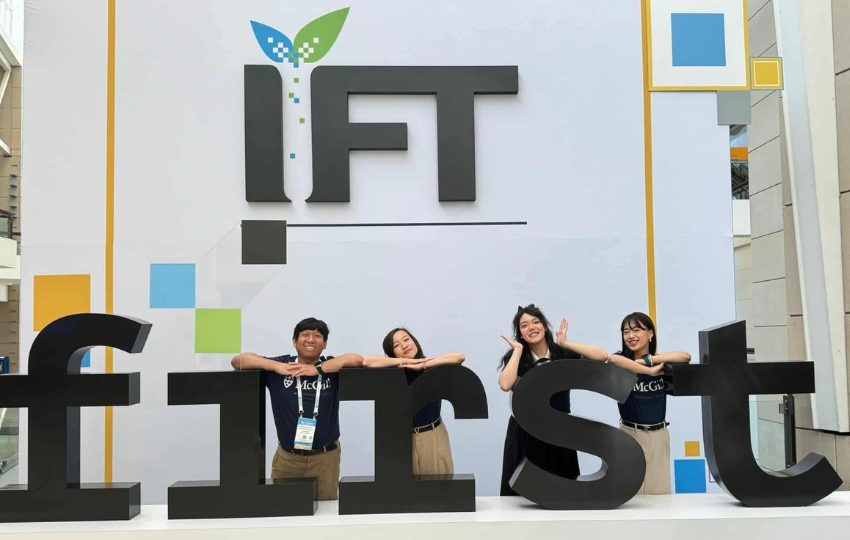 Four students pose and lean on giant letters that spell "first"