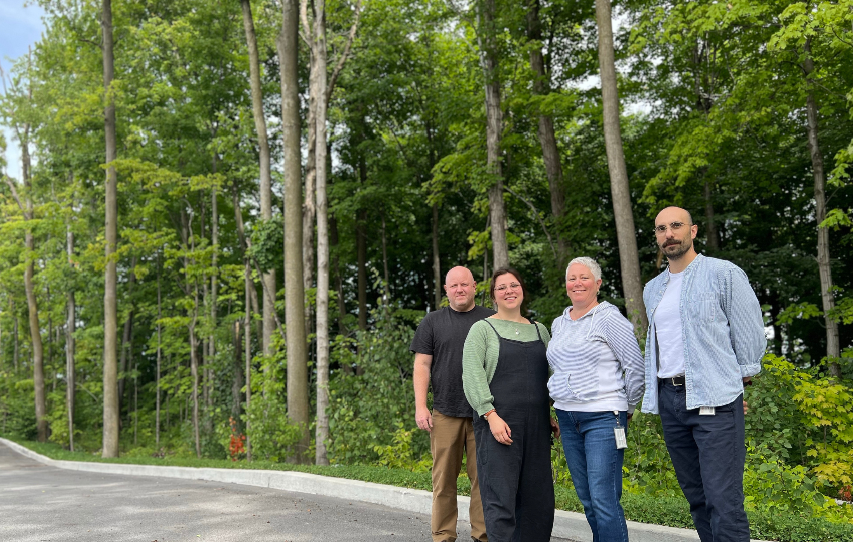 Four staff members posting on the edge of a forest