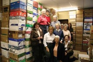 A dozen strong-armed volunteers of the annual McGill Book fair stand in front of a wall of book boxes - one of hundreds they have constructed over the years. / Photo: Tom Inoue