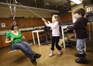 Maggie Weler, WOW Lab manager, is hoisted aloft by her twin children Amy and Jack using the Lab's pulley system. / Photo: Owen Egan