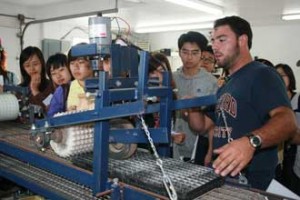 McGill Agricultural Economics grad Alexandre Notaro from Ferme E. Notaro et fils in Sherrington Quebec shows a grouip of visiting Chinese students a lettuce seeding machine built at the farm. / Photo: Caroline Begg